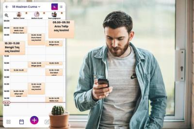 Berber randevu programı kullanıcısı adam telefonuna bakıyor.